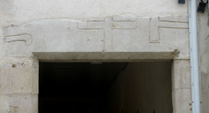 Rue de la Libération, linteau de porte décoré d'une croix entourée d'une serpette et d'un outil taillant (JPG)